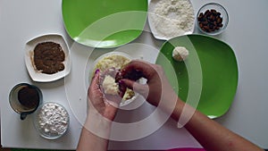 A woman prepares sweets from condensed milk, coconut shavings and almonds. She rolls a ball in her hands, puts almonds inside