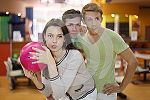 Woman prepares to throw of ball; men look