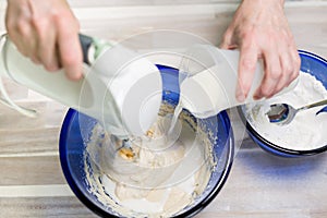 Woman prepares a waffle dough with a stirrer.