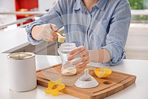 Woman preparing baby formula at table