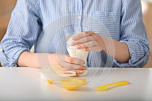 Woman preparing baby formula at table