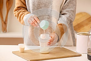 Woman preparing baby milk formula in kitchen