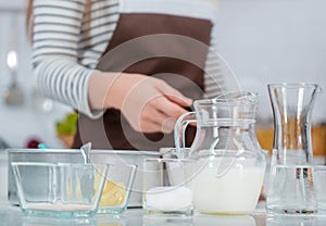 Woman preparing Bakery ingredients on kitchen counter table with milk egg water and flour