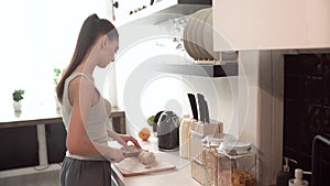 Woman Preparing Breakfast, Cutting Bread On Board In Kitchen