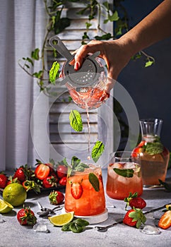 Woman preparing cocktail with fresh strawberries