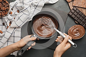 Woman cooking tasty melted chocolate on table in kitchen