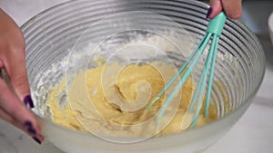 Woman preparing dough mixing ingredients using whisk in the kitchen. Homemade food. Slowmotion shot