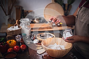 woman preparing equipment and ingredients, flour, vegetables for making pizza