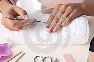 Woman preparing fingernail cuticles at table. At-home manicure photo