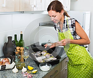 Woman preparing fish on kitchen