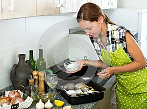 Woman preparing fresh codfish at kitchen