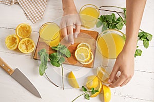 Woman preparing fresh lemon juice on light table