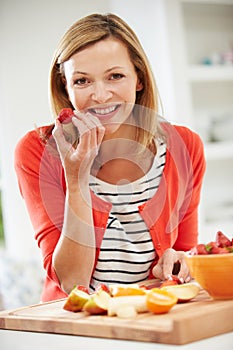 Woman Preparing Fruit Salad In Kitchen