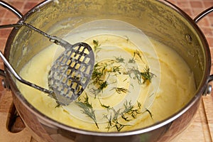 Woman preparing mashed potatoes with stainless potato masher. Cooking process, of mashed potato