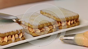 A woman is preparing pastries from cookies and cream. Drizzles cookies with milk to soften. Close-up shot
