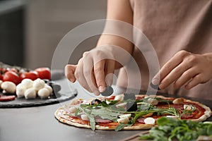 Woman preparing pizza at table in kitchen