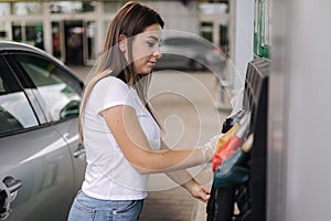 Woman is preparing for refueling at gas station. Female hand filling benzine gasoline fuel in car. Petrol prices concept