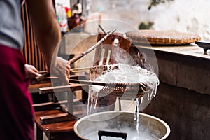 Woman preparing rice noodles traditionally at home