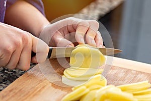 woman preparing sliced potatoes on a wooden board