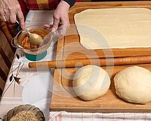 Woman preparing sweet roll cake with jam
