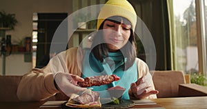 Woman preparing to eat a kebab at a restaurant table. Natural daylight and comfortable setting. Enjoyment of food and