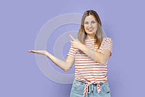 Woman presenting advertising area on her palm and pointing to copy space, holding empty place.