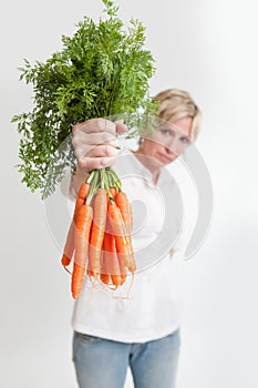 Woman presenting a bunch of carrots