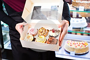 Woman presenting takeaway boxes of confectionery