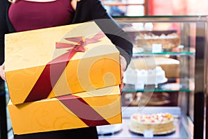 Woman presenting takeaway boxes of confectionery