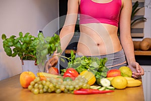 woman presents vegetables, fruits and herbs lying on kitchen table