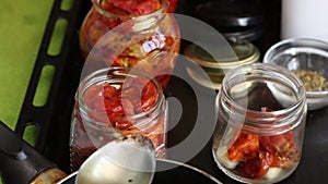 A woman preserves sun-dried tomatoes. Fill them with hot vegetable oil. The camera moves on a slider. Close-up
