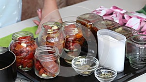 A woman preserves sun-dried tomatoes. Fill them with hot vegetable oil. The camera zooms in on the slider. Close-up