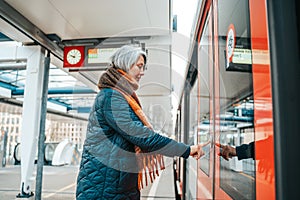 Senior woman press the button to open the door of the train