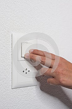 Woman presses the light switch on the wall