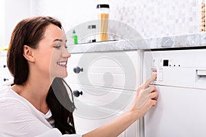 Woman Pressing Button Of Dishwasher