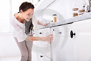 Woman Pressing Button Of Dishwasher