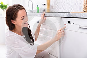 Woman Pressing Button Of Dishwasher