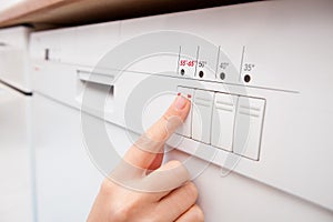 Woman pressing button of dishwasher