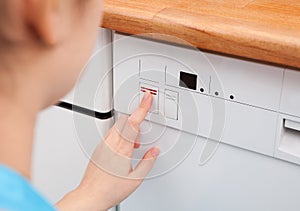 Woman Pressing Button Of Dishwasher