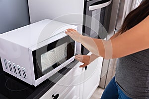 Woman Pressing Button Of Microwave Oven