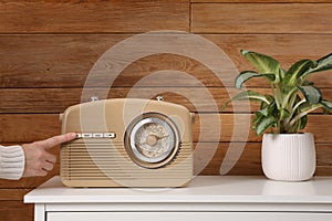 Woman pressing button on radio indoors, closeup