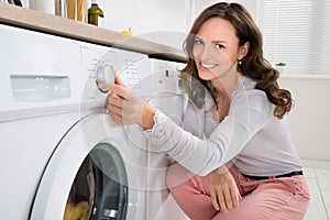 Woman Pressing Button Of Washing Machine