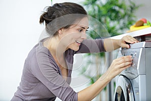 Woman pressing button washing machine for laundry