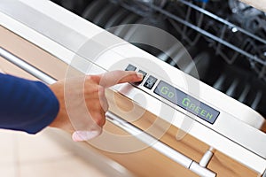 Woman pressing energy saver button on dishwasher