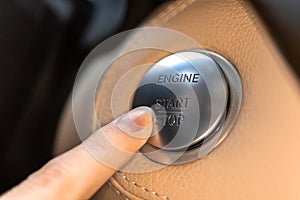Woman pressing engine start and stop button in luxury sport car close-up view