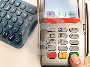 Woman pressing green button on a silver payment machine. Closeup of bank payment terminal. Processing NFC payment device. Top view