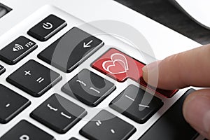 Woman pressing love button on laptop keyboard, closeup. Online dating site