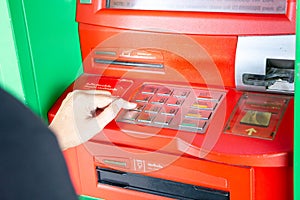 Woman pressing pin number into the ATM