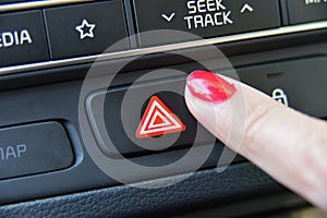 Woman pressing red triangle car hazard warning button