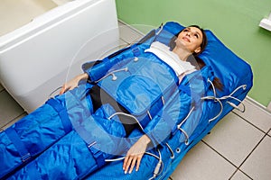 Woman in pressotherapy suit lying down having pressure therapy